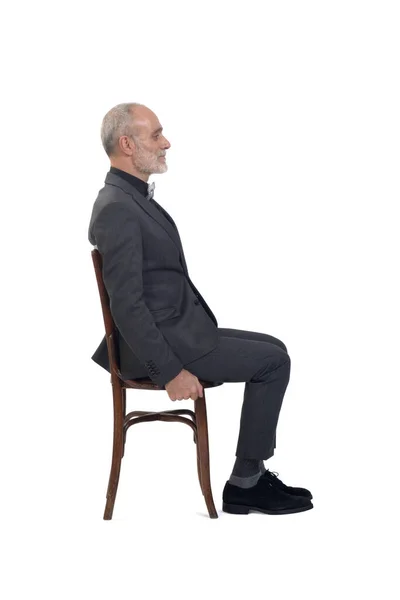 一个穿着西服坐在椅子上 打着白底领带的男人的侧视图 — 图库照片