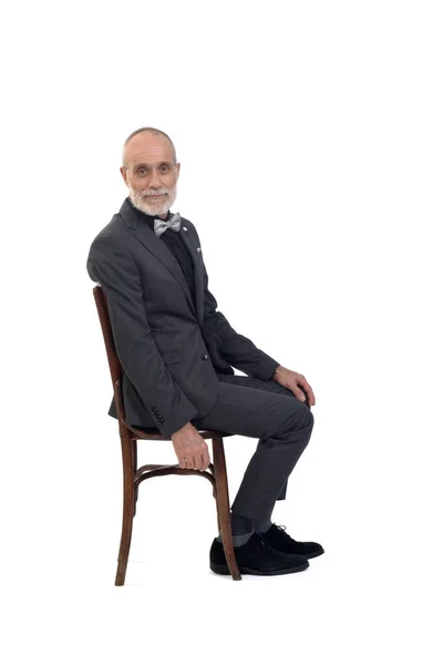 一个男人穿着西服坐在椅子上 打着领带鞠躬 看着白色背景的相机的侧视图 — 图库照片