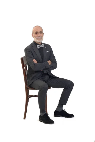 スーツを着た男が椅子に座って腕を組んで横になって白い背景のカメラを見ると — ストック写真