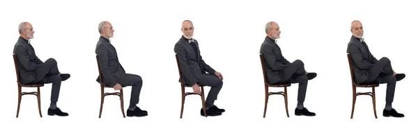 白い背景にスーツと蝶ネクタイで椅子に座っている同じ男のグループのサイドビュー — ストック写真