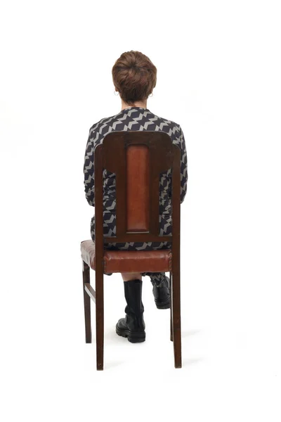Visão Traseira Uma Mulher Vestido Botas Sentadas Cadeira Com Croos — Fotografia de Stock
