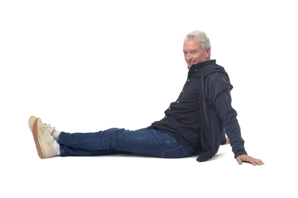 Widok Boku Człowieka Siedzącego Podłodze Rozciągniętymi Nogami Patrzącego Kamerę Białym — Zdjęcie stockowe