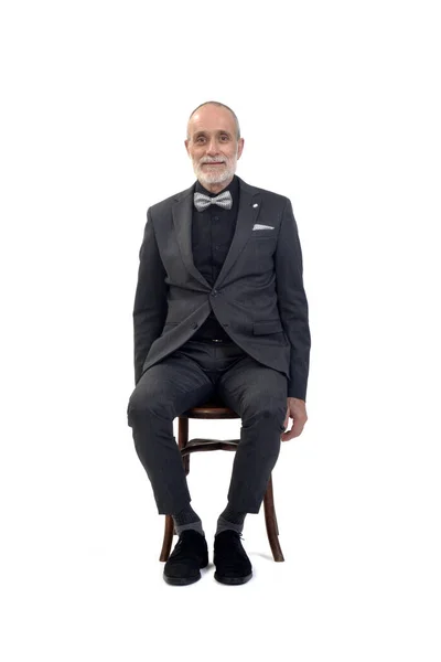 坐在椅子上 身穿西服 打着领结 看着白色背景的相机的男人的前视图 — 图库照片