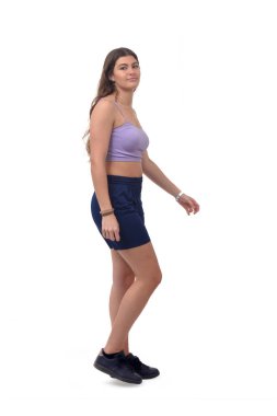 Beyaz arka planda yürüyen ve kameraya bakan genç bir kızın yan görüntüsü