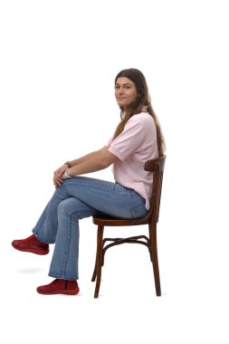 Yan bakışta çapraz bacaklı ve beyaz arka planda kameraya bakan genç bir kız görüyorum.