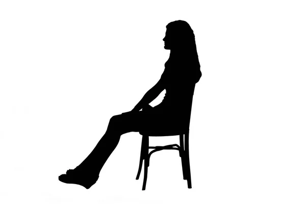 白い背景に伸ばされた足で椅子に座っている若い女の子のシルエットの側面ビュー — ストック写真