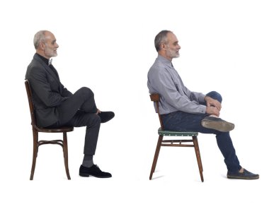 Aynı adamın beyaz arka planda oturan, takım elbise giyen ve günlük giysiler giyen görüntüsü.