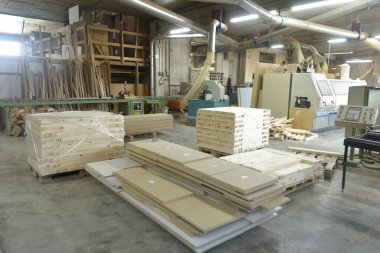 Bir marangozluk endüstrisinin iç görünüşü, makineler ve odun yığını.