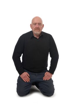 Beyaz arka planda yerde diz çökmüş bir adamın ön görüntüsü.