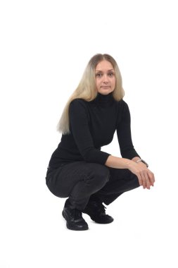 Kıçının üstünde oturan bir kadının beyaz arka plandaki kameraya bakışının yan görüntüsü.