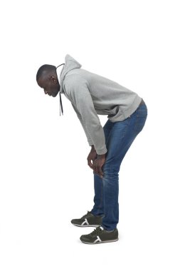 Beyaz arka plana bakan çömelmiş bir adamın yan görünüm portresi.