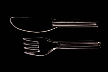 plastic fork and knife on black background clipart