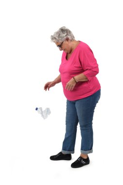 older woman throwing a bottle plastic on the ground on white background clipart