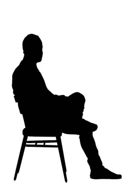 Sandalyeye oturmuş kameraya bakan bir adamın yan görünüşü. 