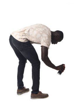 side view of a crouching man painting with a spray on white background