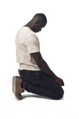side view of a man sitting on his knees look down on white background