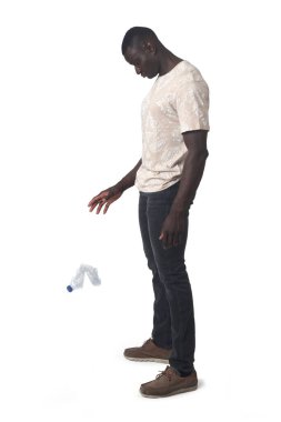 side view of a a men throwing a plastic water bottle on the floor on white background
