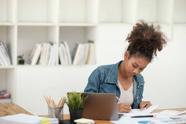 Smart African women working in beautiful office, working on Laptop, use the phone, talking on the cellphone. . High quality photo
