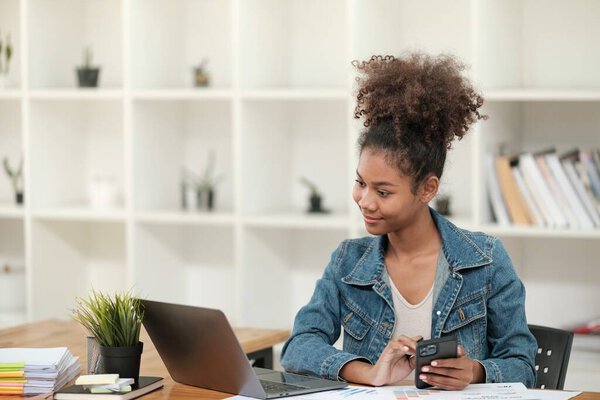 Smart African women working in beautiful office, working on Laptop, use the phone, talking on the cellphone. . High quality photo