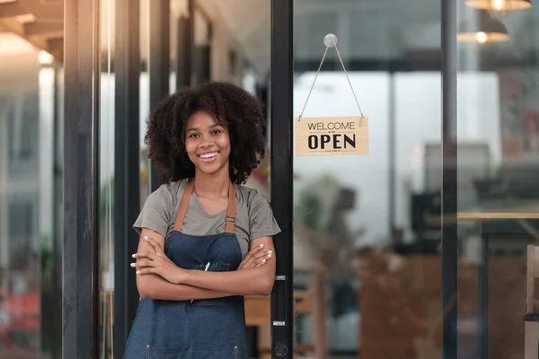 Successful african woman in apron standing coffee shop door. Happy small business owner holding tablet and working. Smiling portrait of SME entrepreneur seller business standing with copy space. High
