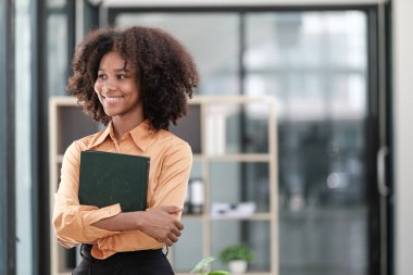 Mutlu Afrikalı iş kadını dijital aletlerle sohbet ediyor, cep telefonu tutuyor, dizüstü bilgisayar kullanıyor, kameraya bakıyor, gülümsüyor. Ev işyerindeki serbest çalışan kafasından vurulmuş. Yüksek kalite