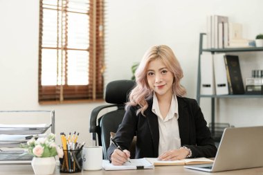 Ofiste dizüstü bilgisayarı kapat, Asyalı mutlu iş kadını resmi takım elbiseli iş yerinde çalışıyor. Çekici bayan ofis çalışanı gülümsemesi. Yüksek kalite fotoğraf
