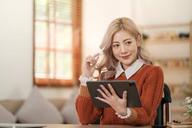 Odadaki kanepede oturan Asyalı genç bir kadın akıllı telefon kullanıyor. İnternetten alışveriş sipariş et. Yüksek kalite fotoğraf