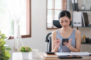 Güzel Asyalı genç kadın sosyal medyayla günlük işler yapıyor. Serbest çalışan kadın online satış pazarlaması yapıyor. İnternetten alışveriş. Merhaba kaliteli fotoğraf..