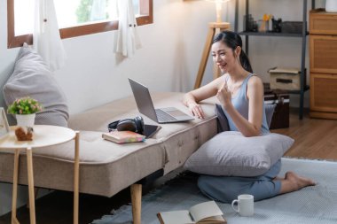 Evde bilgisayarla çalışan Asyalı genç bir kadın. Evde çalışmak, video konferansı, video görüşmesi, öğrenci öğrenme çevrimiçi sınıfı, online alışveriş yüksek kaliteli fotoğraf.