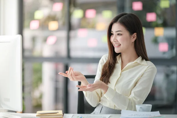 stock image Photo of attractive woman sitting at desk working on computer looking at screen, smiling, wearing yellow shirt and glasses, typing on keyboard, doing project for university. High quality photo