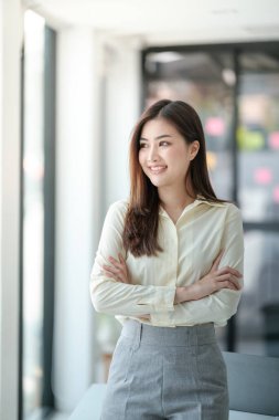 Ofisin penceresinden bakan gülümseyen çekici Asyalı kadın. Yüksek kalite fotoğraf.