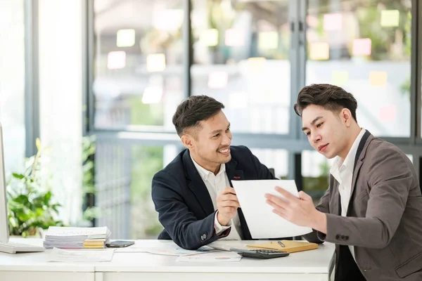 stock image Smiling young businessman discussing something positive with his mature colleague, and using a digital tablet together. High quality photo