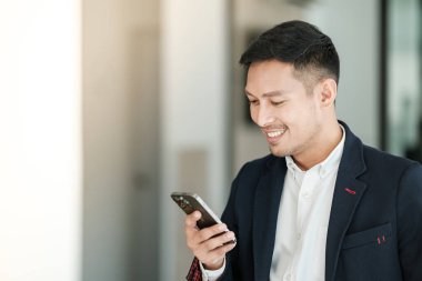 Asyalı iş adamı cep telefonu kullanıyor. Sohbet etmek, SMS yazmak ya da sunum yapmak. Yüksek kalite fotoğraf