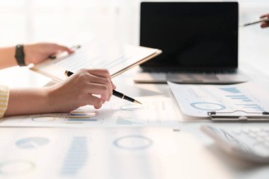 İki Asyalı erkek ve kadın iş adamından oluşan bir ekip ofis masasında dizüstü bilgisayar ve dijital tabletle yeni finansal grafik verilerini tartışıyor. Yüksek kalite fotoğraf