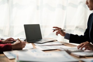 İki Asyalı erkek ve kadın iş adamından oluşan bir ekip ofis masasında dizüstü bilgisayar ve dijital tabletle yeni finansal grafik verilerini tartışıyor. Yüksek kalite fotoğraf