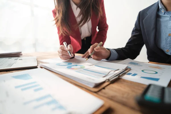 stock image Team of two asian male and female business people working together discussing new financial graph data on office table with laptop and digital tablet. High quality photo