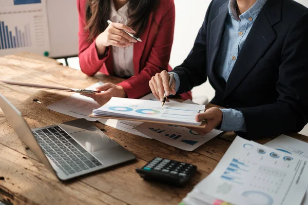 stock image Team of two asian male and female business people working together discussing new financial graph data on office table with laptop and digital tablet. High quality photo