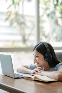 Güzel Asyalı kadın internette dizüstü bilgisayarla oturma odasında öğreniyor. Yüksek kalite fotoğraf