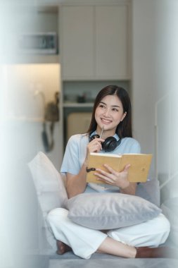 Güzel Asyalı kadın internette dizüstü bilgisayarla oturma odasında öğreniyor. Yüksek kalite fotoğraf