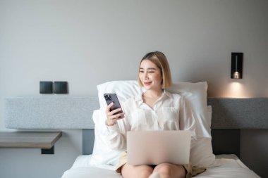 Evde Yatakta Dizüstü bilgisayarla mesaj bırakan neşeli Asyalı bir kadın. Yüksek kalite fotoğraf