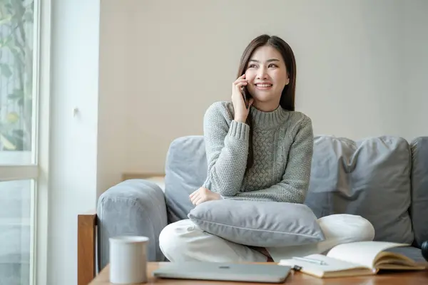 stock image Asian female talking on the phone and writing a book with a smiling face, Working at home, Home lifestyle, Stay home. High quality photo