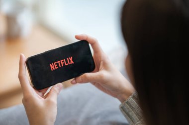 CHIANG MAI, THAILAND - 23 Haziran 2023: Bir kadın Netflix eğlence platformlu elmalı iPhone 14 'ü evinde tutuyor. Yüksek kalite fotoğraf