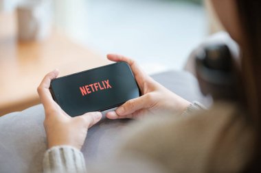 CHIANG MAI, THAILAND - 23 Haziran 2023: Bir kadın Netflix eğlence platformlu elmalı iPhone 14 'ü evinde tutuyor. Yüksek kalite fotoğraf