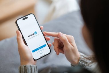 CHIANG MAI, Tayland - Nisan. 19.2023: Ekranda LinkedIn uygulaması olan iPhone 14 Pro Max 'i tutan kadın. Instagram popüler bir online sosyal ağ hizmetidir. Yüksek kalite fotoğraf