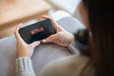 CHIANG MAI, THAILAND - 23 Haziran 2023: Bir kadın Netflix eğlence platformlu elmalı iPhone 14 'ü evinde tutuyor. Yüksek kalite fotoğraf
