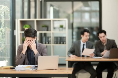 İş adamları ofisinde dizüstü bilgisayarlarıyla oturup, kendilerini baskı altında ve yorgun hissediyorlar. Yüksek kalite fotoğraf