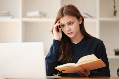 Düşünüyorum da, güzel beyaz bir kız öğrenci uzaktan çalışıyor. Evde dizüstü bilgisayar ve not defteriyle bir masada oturuyor ve bir video konferansı izliyor. Yüksek kalite fotoğraf