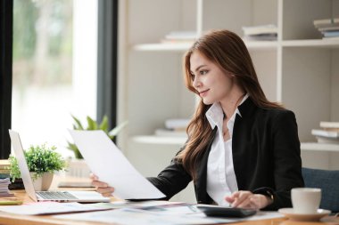 Asyalı İş kadını, bir ofis masası, vergi, rapor, muhasebe, istatistik ve analitik araştırma konseptinde matematik finansmanı için hesap makinesi ve dizüstü bilgisayar kullanıyor. Yüksek kalite fotoğraf