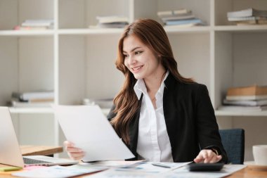 Asyalı İş kadını, bir ofis masası, vergi, rapor, muhasebe, istatistik ve analitik araştırma konseptinde matematik finansmanı için hesap makinesi ve dizüstü bilgisayar kullanıyor. Yüksek kalite fotoğraf