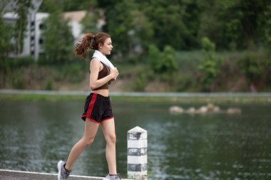 Sağlıklı Asyalı kadın dışarıda koşuyor. Koşan sporcu kız. Açık hava parkında kadın egzersizi. Gün batımı ya da gün doğumu. Yüksek kalite fotoğraf